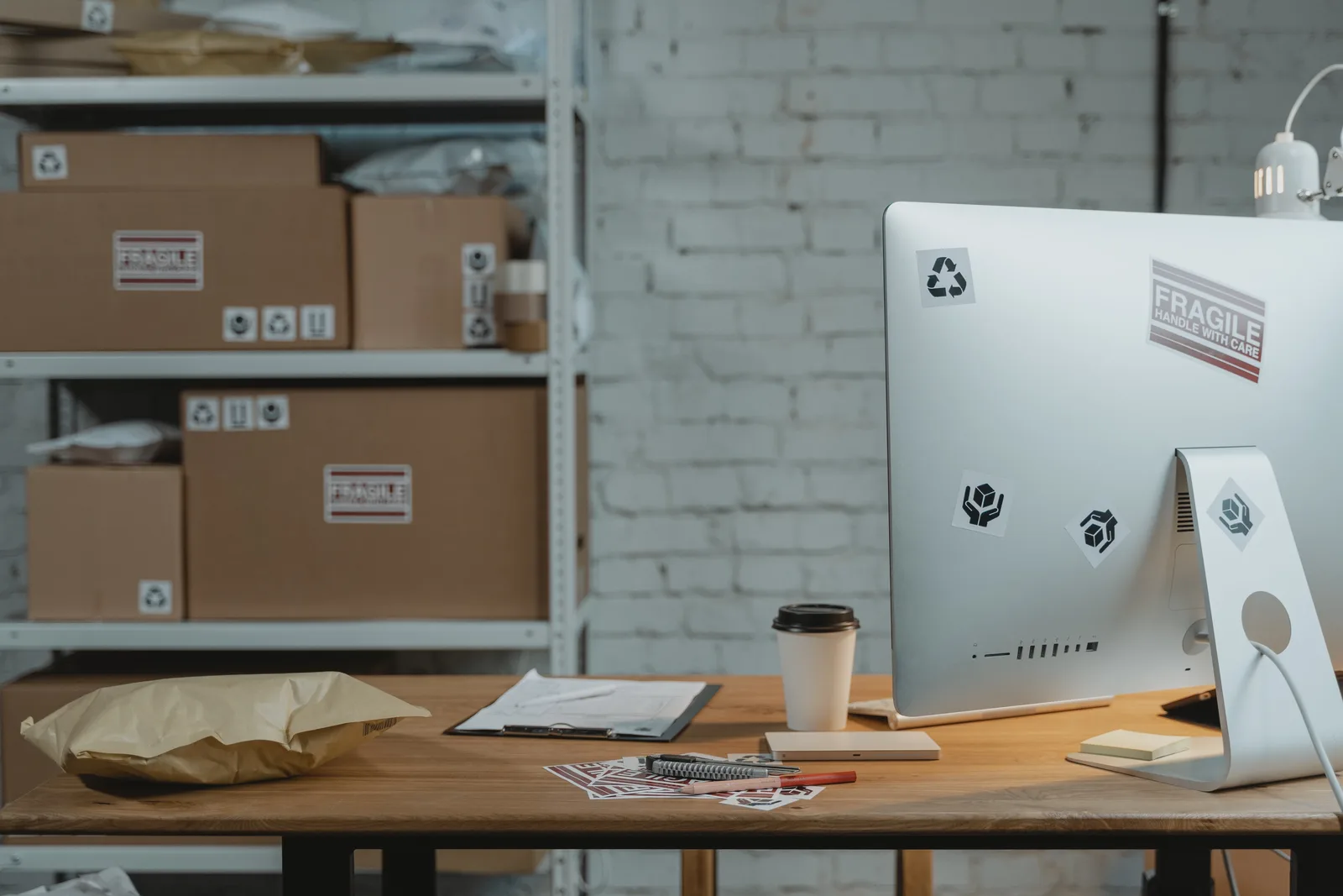 Contemporary office setup with a computer, coffee, and parcels on a wooden desk.